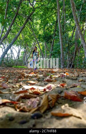 Amerika, Karibik, Großantillen, Dominikanische Republik, Cabarete, Frau Spaziergänge durch einen schattigen Wald in der Nähe des Strandes in Richtung Natura Cabana Boutique Hotel & Spa Stockfoto