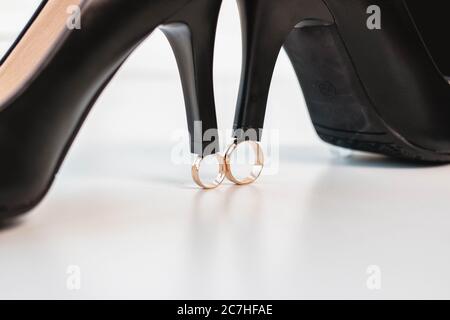 Eheringe der Braut und des Bräutigams und schwarze Schuhe auf weißem Hintergrund. Hochzeitstag. Stockfoto