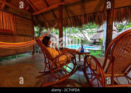 Amerika, Karibik, Großantillen, Dominikanische Republik, Cabarete, Frau auf der Terrasse ihres Bungalows im Natura Cabana Boutique Hotel & Spa Stockfoto