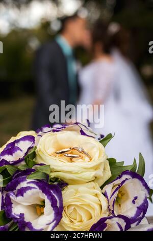 Eheringe auf einem Strauß gelber und lilafarbener Blumen Stockfoto