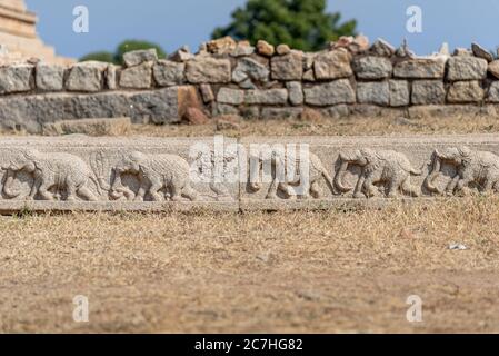Steinrand mit Elefantenrelief und verwitterte Wand im Hintergrund Stockfoto