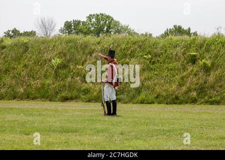 NIAGARA ON THE LAKE, KANADA - 20. Jun 2019: Schauspieler, der wie ein Soldat aus dem 18. Jahrhundert gekleidet ist, bereitet sich darauf vor, eine Muskete zu feuern. Die Lage ist Fort George a Histo Stockfoto