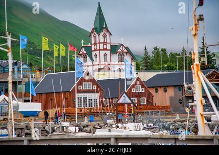 HUSAVIK, ISLAND - 5. AUGUST 2019: Husaviks farbenfrohe Häuser und Stadthafen in Island. Blick auf einen bewölkten Sommernachmittag. Stockfoto