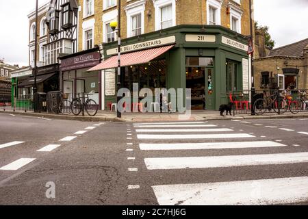 London England - August 20 2015; Fußgängerüberweg markiert den Weg über die Straße zu einem traditionellen mittelschweren Vorstadtgebäude mit Delikatessengeschäft auf der Straße. Stockfoto