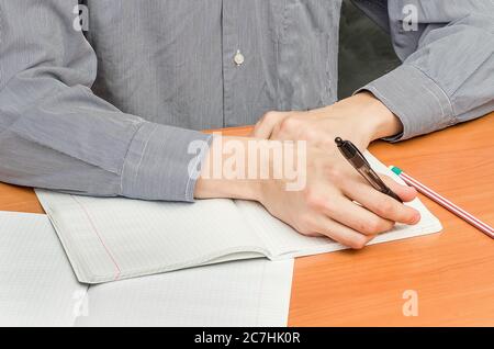 Ein Student im Hemd sitzt an einem Tisch und schreibt eine Zusammenfassung. Schulunterricht, Unterricht an der Universität. Stockfoto