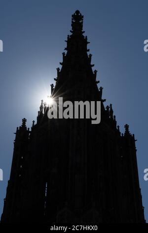 Die Silhouette des Domturms des Ulmer Münsters mit einem Sonnenstern Stockfoto