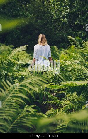 Vertikale Aufnahme eines Weibchens, das zwischen den Farnpflanzen steht Auf einem Feld Stockfoto