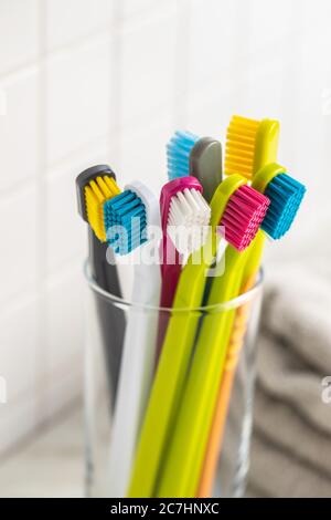 Verschiedene bunte Zahnbürsten in Tasse. Stockfoto