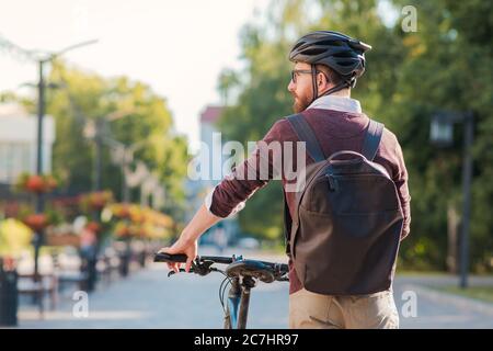 Porträt eines männlichen Pendlers mit Fahrradhelm in einer Stadt. Sicheres Radfahren in der Stadt, Fahrrad pendeln, aktive städtischen Lebensstil Bild Stockfoto