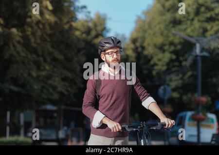 Porträt eines männlichen Pendlers mit Fahrradhelm in einer Stadt. Sicheres Radfahren in der Stadt, Fahrrad pendeln, aktive städtischen Lebensstil Bild Stockfoto