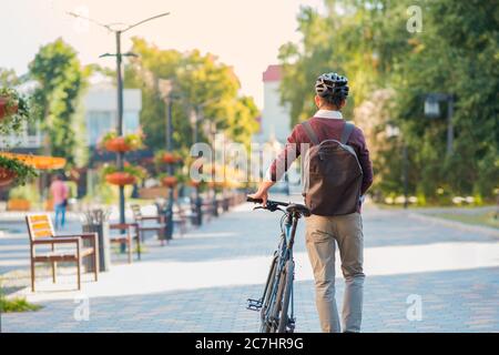 Männer Pendler tragen Fahrrad Helm zu Fuß entfernt. Sicheres Radfahren in der Stadt, Fahrrad pendeln, aktive städtischen Lebensstil Bild Stockfoto