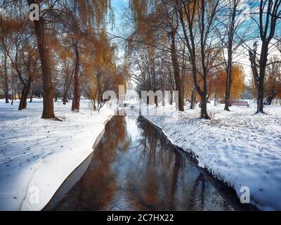 Landschaftlich schöner Blick auf den Fluss und die Bäume mit dem ersten Schnee. Gefallene Blätter auf dem Schnee Stockfoto