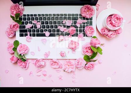 Postkartenvorlage. Die Laptop-Tastatur ist mit Blumen, einem weißen Tasse rosa Hintergrund bestreut. Valentinstag. Frauentag. Festlicher Hintergrund. Morgen Stockfoto