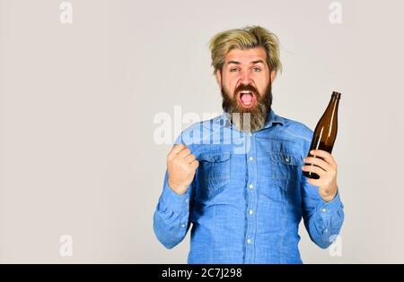 Sport Liebhaber aufmuntern. Reifer Mann hält Glasflasche Bier. Betrunken Hipster männlichen Handwerk Flaschenbier. Glücklicher Mann halten volle Glasflasche in der Hand. Männlich hält Flasche Bier. Hipster Rest in Pub. Stockfoto