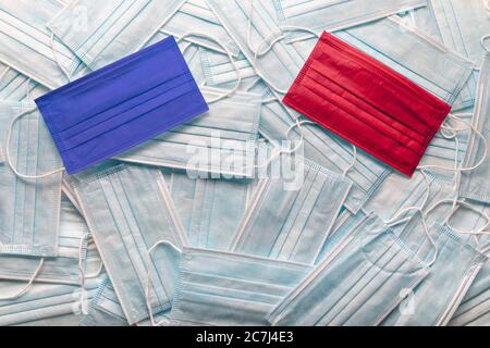 Republikanische rote und demokratische blaue medizinische Gesichtsmasken, die auf einem Haufen anderer Gesichtsmasken ruhen. Stockfoto
