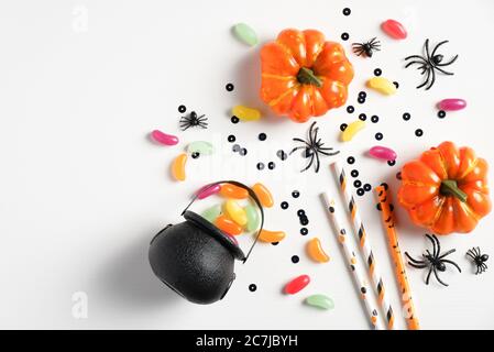 Happy halloween Feiertagskonzept. Halloween-Dekorationen, Topf mit süßen Bonbons, orange Kürbisse, Spinnen, Konfetti auf weißem Hintergrund. Halloween-Teil Stockfoto