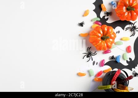 Halloween Dekorationen auf weißem Hintergrund. Flache Lay-Zusammensetzung mit orangen Kürbissen, süßen Bonbons, Topf, Spinnen, Fledermäuse. Halloween Feiertagsgruß ca. Stockfoto