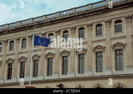 Low-Angle-Aufnahme der Flagge der Europäischen Union vor Eines historischen Betongebäudes Stockfoto