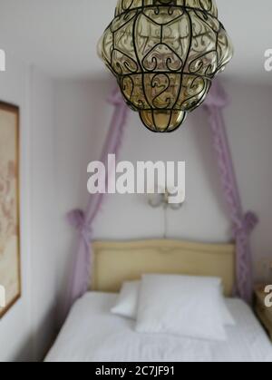 Vertikale selektive Fokusaufnahme eines Lüsters, der über einem hängt Bett Stockfoto