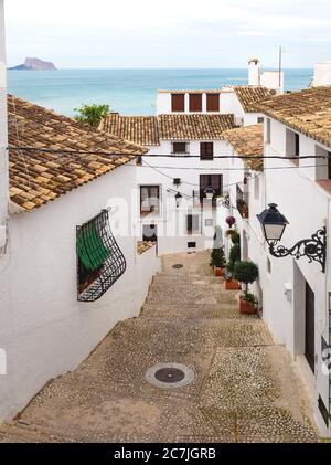 Treppen in einer schmalen Straße mit weiß getünchten Häusern und Blick über das Meer und den Felsen von Calpe in der Altstadt von Altea, Costa Blanca, Spanien Stockfoto