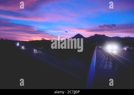 Abstrakt verschwommenes Bergpanorama der Autobahn mit aufhellenden Autos bei dramatischem Sonnenuntergang, Altea, Costa Blanca, Spanien Stockfoto