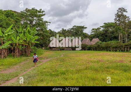 Indigene ecuadorianische Kichwa Mädchen zur Schule in ihrem Dorf mit traditioneller Hüttenarchitektur, Amazonas Regenwald, Yasuni Nationalpark, Ecuador. Stockfoto