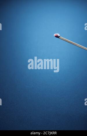 Vertikale Aufnahme eines verbrannten Streichholzstachel mit einer blauen Wand Im Hintergrund Stockfoto
