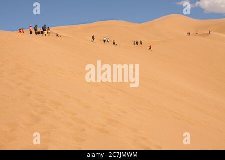 Gruppen von Wanderern wandern auf riesigen Wüstensanddünen im Great Sand Dunes National Park in Alamosa, Colorado, USA Stockfoto