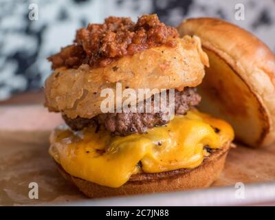 Nahaufnahme eines Burgers mit geschmolzenem Käse gegen eine verschwommene Hintergrund Stockfoto