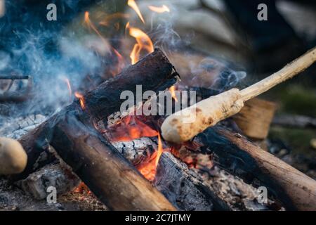 Brotteig auf einem Holzstab, der in einem gekocht wird Lagerfeuer Stockfoto