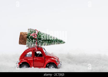 Rotes Auto Modell transportiert Mini Weihnachtsbaum, Kunstschnee, weißer Hintergrund, Stockfoto