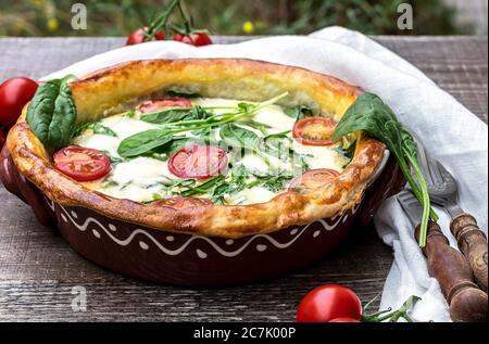 Nahaufnahme und selektiver Fokus von vegetarischen Spinatkuchen oder Quiche mit Feta und Mozzarella Käse mit Tomaten. Stockfoto