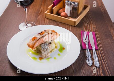 Gourmet-Lachssteak im Ofen gebacken, serviert auf einem Kissen aus Risotto und rotem Kaviar als köstliches Meeresfrüchte-Gericht zum Abendessen Stockfoto