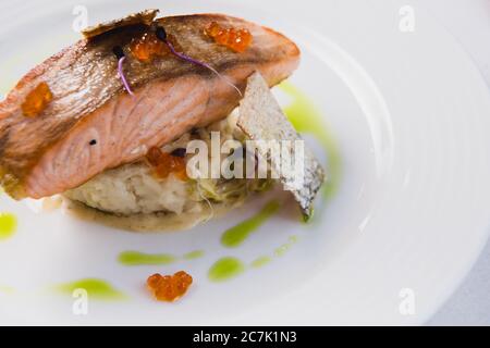 Gourmet-Lachssteak im Ofen gebacken, serviert auf einem Kissen aus Risotto und rotem Kaviar als köstliches Meeresfrüchte-Gericht zum Abendessen Stockfoto