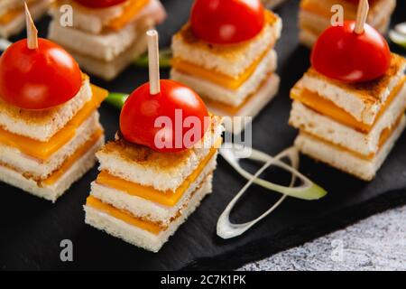 Käsekanapes verzierte Tomaten auf schwarzem Teller Stockfoto