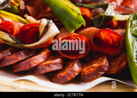 Verschiedene Fleisch- und Wurstsorten sowie gegrilltes Gemüse auf einem runden Teller Stockfoto