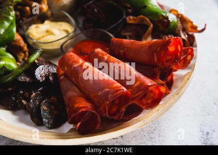 Verschiedene Fleisch- und Wurstsorten sowie gegrilltes Gemüse auf einem runden Teller Stockfoto