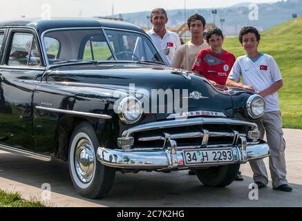 Besucher des Izmit Turkish Oil Wrestling Festival in der Türkei bewundern ein Oldtimer-Plymouth-Auto. Stockfoto