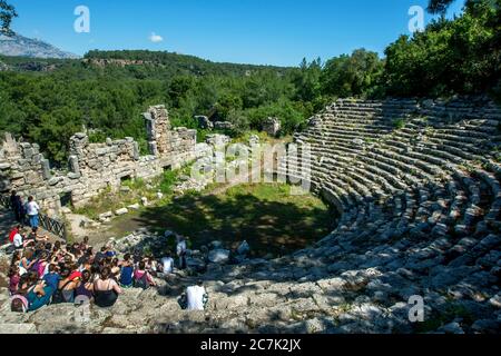 Touristen sitzen unter den Ruinen des Theaters in der antiken griechischen und römischen Stadt Phaselis in Kemer in der Türkei, die aus dem Jahr 700 v. Chr. stammt. Stockfoto