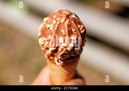 Hält in einem Kegel Eis mit Schokolade Stockfoto
