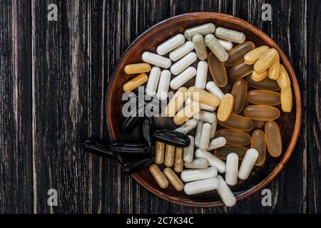 Multivitamin Pillen auf einem Tonteller, auf einem Vintage-Holztisch Stockfoto