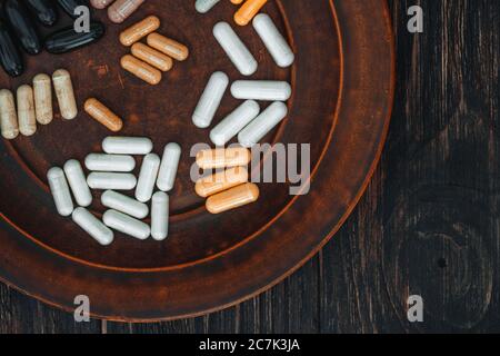 Multivitamin Pillen auf einem Tonteller, auf einem Vintage-Holztisch Stockfoto