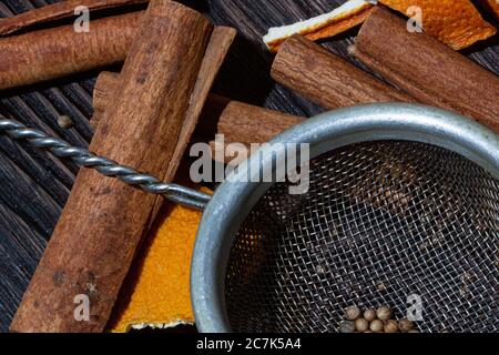 Zimt, Orangenkrusten, Gewürze und Metallsieb auf einem Holztisch Stockfoto