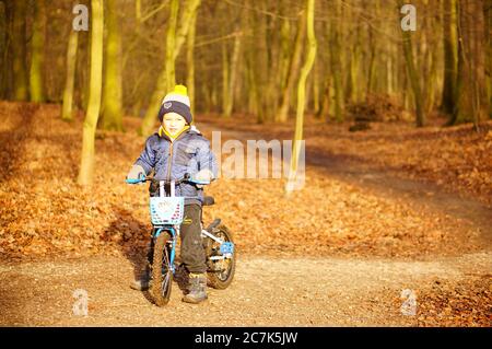 POZNAN, POLEN - 12. Jan 2020: Kleiner Junge sitzt auf einem Fahrrad in einem Wald an einem kalten Wintertag. Stockfoto