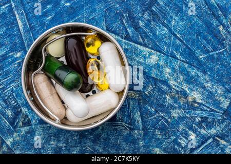 Biologisch aktive Zusatzstoffe in einem kleinen Eisenbehälter, auf einer blauen Holzoberfläche Stockfoto