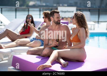 Schöne lockige Frau auf einer Matratze sitzen und mit einem Mann sprechen Stockfoto