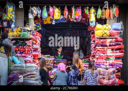 Mandalay, Myanmar - Sprechzeit in einem Geschäft Verkauf bunten Decken und Kissen. Zay Cho Markt, der größte traditionelle Markt in Myanmar. Stockfoto