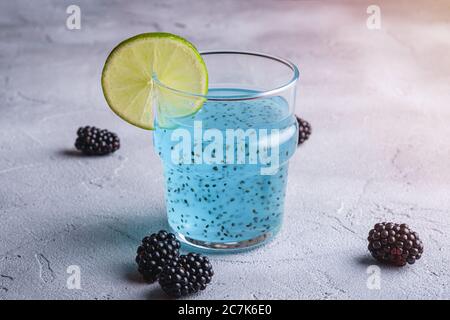 Leckere blaue Cocktail-Drink mit Basilikum Chia Samen, Zitruslime Scheibe und Brombeere im Glas, gesunde Sommergetränk, Stein Beton Hintergrund Stockfoto