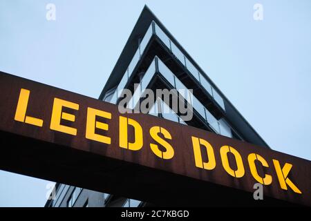 LEEDS, VEREINIGTES KÖNIGREICH - Jan 11, 2020: Horizontale Aufnahme eines Leeds Dock-Schildes in einer wolkigen Dämmerung Nacht mit einem Wohnblock hinter sich Stockfoto