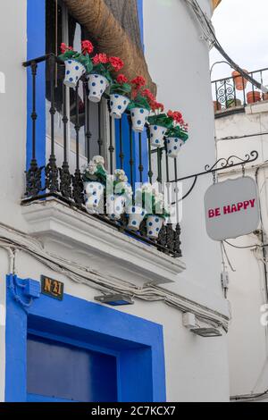 Ein farbenfroher Balkon mit Topfpflanzen über dem Eingang zum Mode-Accessoires-Shop „Be Happy“ in Córdoba Calle Fernández Ruano Stockfoto